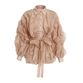 Chemisier sophistiqué à col pointu, boutonné sur le devant, taille nouée, manches longues, volants superposés